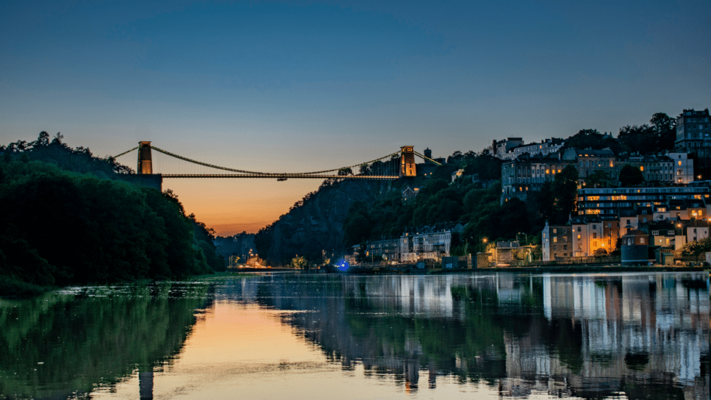 View of Bristol city center featuring modern tech offices alongside historic landmarks like the Clifton Suspension Bridge over the Avon Gorge; brightly coloured houses adorn the hillsides, and hot air balloons fill the summer sky—symbolizing BookingLive's presence in a vibrant city renowned for its technology sector, rich heritage, and lively festivals